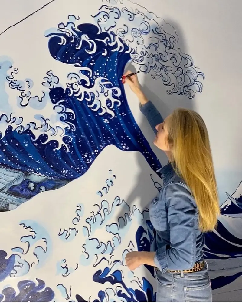 Virginie Georgeault peignant une grande vague bleue